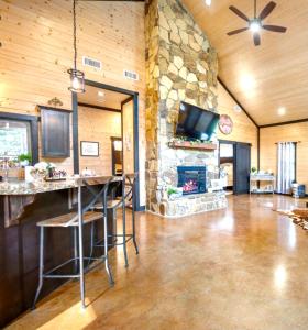 a living room with a stone fireplace and a tv at Knotty and Nice Luxury Cabin in Broken Bow
