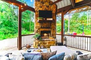 a screened in porch with a stone fireplace at Knotty and Nice Luxury Cabin in Broken Bow