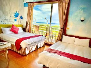 1 dormitorio con 2 camas y una ventana con vistas al océano en Fei Li Jin Hotel en Kenting