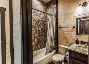 a bathroom with a toilet and a tub and a sink at Knotty and Nice Luxury Cabin in Broken Bow +34 photos