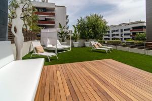a rooftop patio with a deck with chairs and grass at Sitges Spaces Garden Paradise 3 bedroom, 3 bathroom, huge PRIVATE garden-terrace, pool- sleeps up to 8 in Sitges