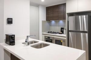 a kitchen with a stainless steel refrigerator, stove and sink at Meriton Suites Southport in Gold Coast