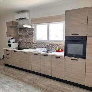 a kitchen with wooden cabinets and a sink and a window at F5 Modern and Bright Apartment in Malta in Msida