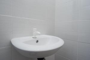 a white sink in a white tiled bathroom at RedDoorz Plus @ Jl Pemuda Pati in Pati