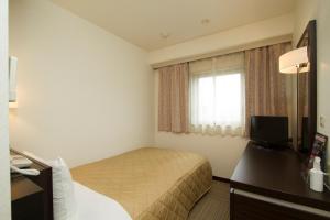 a hotel room with a bed and a window at Ariston Inn Kanda Kitakyusyu Airport in Kanda