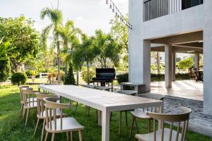 a white table and chairs in a yard with a piano at Pirom Garden Private Villa in North Pattaya