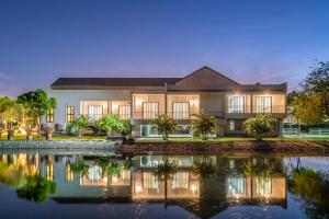 a building with its reflection in the water at night at Pirom Garden Private Villa in Pattaya North