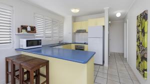 uma cozinha com um balcão azul e um frigorífico em #4 Shorebreak, Kings Beach em Caloundra