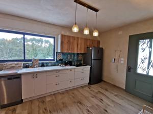 a kitchen with white cabinets and a black refrigerator at לילה בחוף אכזיב in Gesher HaZiw