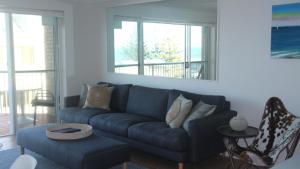 uma sala de estar com um sofá azul e uma janela em Unit 5 Sanctuary Shores, Kings Beach - Free Wifi! em Caloundra