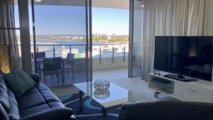 a living room with a couch and a large screen television at Amazing Views, Walk Everywhere! in Caloundra