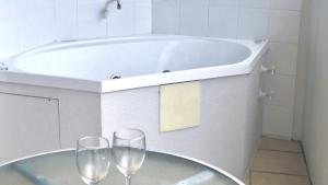 two wine glasses on a table in front of a tub at #55 Grand Pacific Resort, Outdoor Spa With A View! in Caloundra