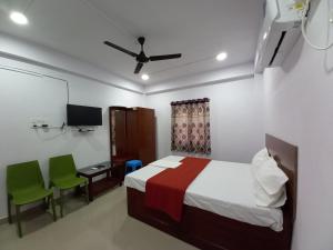 a bedroom with a bed and a desk and a tv at VEERAS HOME STAY in Port Blair