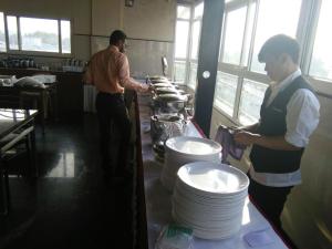 two men standing in a kitchen with plates on a counter at Hotel U.T.ELITE in Bangalore