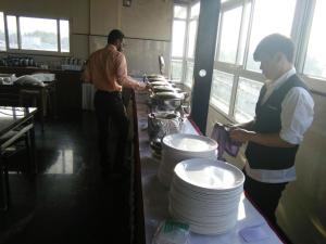 deux hommes debout dans une cuisine avec plaques sur un comptoir dans l'établissement Hotel U.T.ELITE, à Bangalore