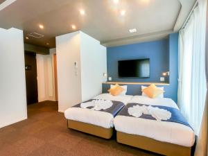 大阪Hotel S-Presso Central的卧室里有一张大床，墙壁是蓝色的