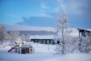 Ein schneebedeckter Hof mit einem Gebäude im Hintergrund in der Unterkunft Camp Ripan in Kiruna