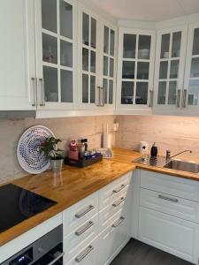 a kitchen with white cabinets and a wooden counter top at Koselig maritim leilighet sentralt i Stavern in Stavern +16 photos