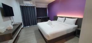 een slaapkamer met een groot bed en een paarse muur bij ทริปเปอร์ โฮเทล in Ubon Ratchathani
