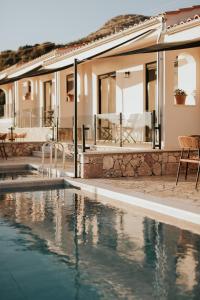 a villa with a swimming pool in front of a house at Elia Luxury Suites in Plataria