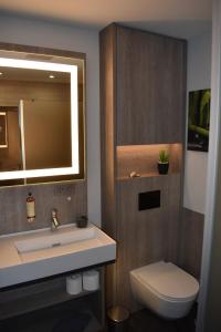 a bathroom with a sink and a toilet and a mirror at Hotel Neue Stuben in Wolfsburg