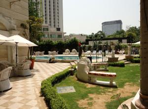 einen Innenhof mit einem Pool und Stühlen sowie ein Gebäude in der Unterkunft Hotel The Royal Plaza in Neu-Delhi