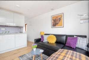 een woonkamer met een zwarte leren bank en paarse kussens bij The Nook in Inverness