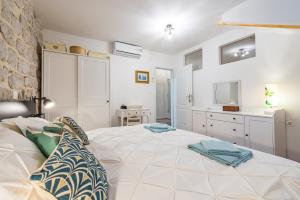 a bedroom with a large white bed and a kitchen at Villa Dovecote with Private Sauna, Jacuzzi & Gym in Ston