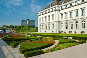 - un grand bâtiment blanc avec un jardin en face dans l'établissement Mercure Hotel Koblenz, à Coblence