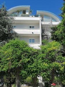 un edificio blanco con árboles delante de él en Family Suite Appartments Orchidea Blu, en Rímini