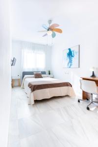 biała sypialnia z łóżkiem i wentylatorem sufitowym w obiekcie Piso encantador junto al mar, relax, tranquilidad w mieście Torre del Mar