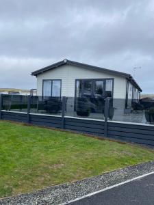 a white house with a black fence and grass at Morwenna Lodge - Waves of the Ocean in Bude