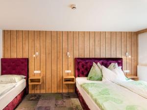 two beds in a room with wooden walls at Apartment in Wald near Zillertal Ski Slopes in Wald im Pinzgau