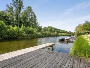 a wooden dock on a river with a boat at Modern Villa in Harderwijk with Sauna and Jacuzzi in Harderwijk