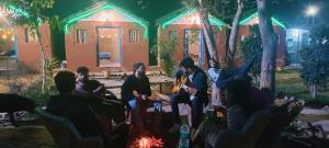 a group of people sitting around a fire in front of a house at Village Homestay in Agra