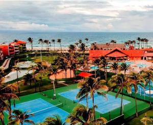 a resort with two pools and palm trees and the ocean at Apartamento Aquaville Pé na areia e Água coco in Aquiraz