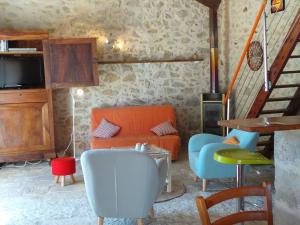 ein Wohnzimmer mit einem orangenen Sofa und Stühlen in der Unterkunft Stone house in a vineyard, with swimming pool, near Bordeaux in Monprimblanc