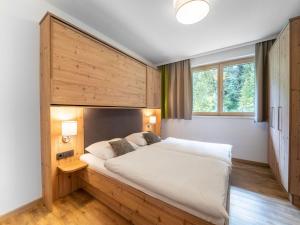 a bedroom with a large bed with a wooden headboard at Spacious Chalet with Sauna in Saalbach Hinterglemm in Saalbach-Hinterglemm