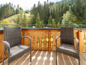 two chairs on a deck with a fence and trees at Spacious Chalet with Sauna in Saalbach Hinterglemm in Saalbach-Hinterglemm