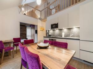 una cucina e una sala da pranzo con tavolo in legno e sedie viola di Apartment in St Georgen Salzburg near ski area a Fürstau