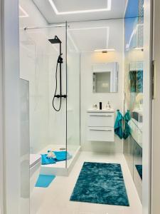 a bathroom with a glass shower stall and a blue rug at Aquarius Santorini in Boszkowo