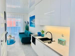 a kitchen with white cabinets and a blue couch at Aquarius Santorini in Boszkowo