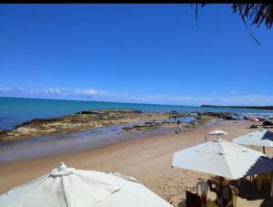 a beach with white umbrellas and the ocean at Casa Japa Beach in Japaratinga