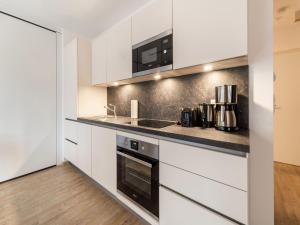 una cocina con armarios blancos y electrodomésticos negros en Apartment in St Georgen Salzburg near ski area, en Fürstau