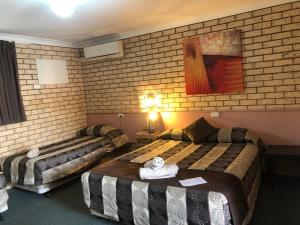 a hotel room with two beds and a painting on the wall at Alamo Motor Inn in Nyngan