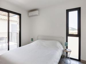 a white bedroom with a bed and a balcony at Attractive Holiday Home in Malauc ne with Terrace in Malaucène
