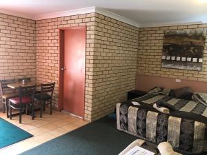 a room with two beds and a table and a dining room at Alamo Motor Inn in Nyngan