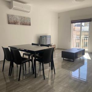 ein Esszimmer mit einem schwarzen Tisch und Stühlen in der Unterkunft F10 Modern and Bright Apartment in Malta in Msida