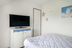 ein Schlafzimmer mit einem Bett und einem Flachbildfernseher in der Unterkunft Face à la marina belle maison pour 6 in Arzon