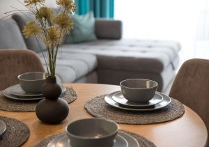 a table with two cups and a vase with flowers on it at Marina Apartment by Dora in Keszthely